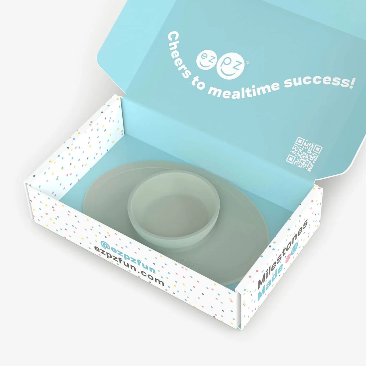 Open box containing a green baby bowl with 'ezpz' branding and text on a light gray background.