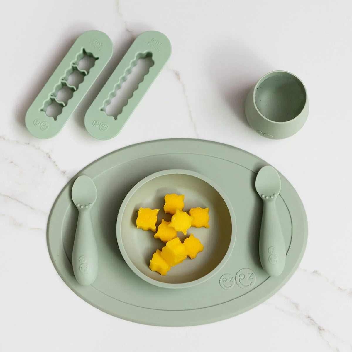Children's green dining set with bowl, plate, cup, and utensils on a white background