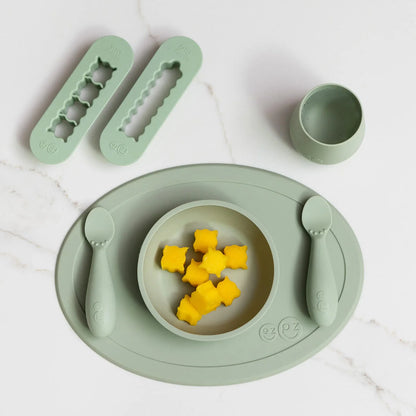 Children's green dining set with bowl, plate, cup, and utensils on a white background